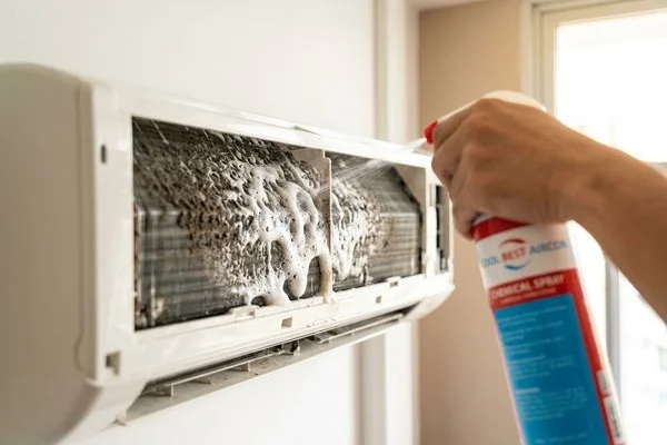 Billy Aircon technician spraying chemical solution on evaporator coil in Singapore HDB flat